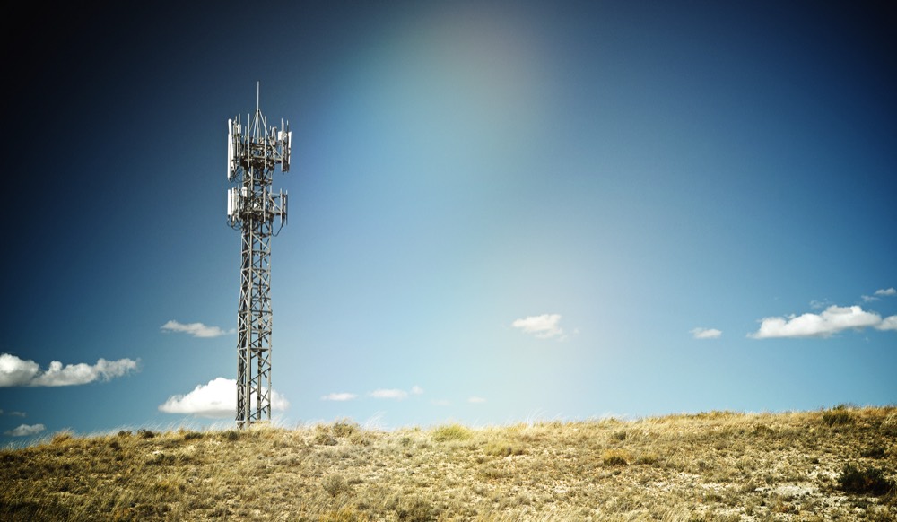 Communications tower on a grassy high-desert ridge under a blue sky